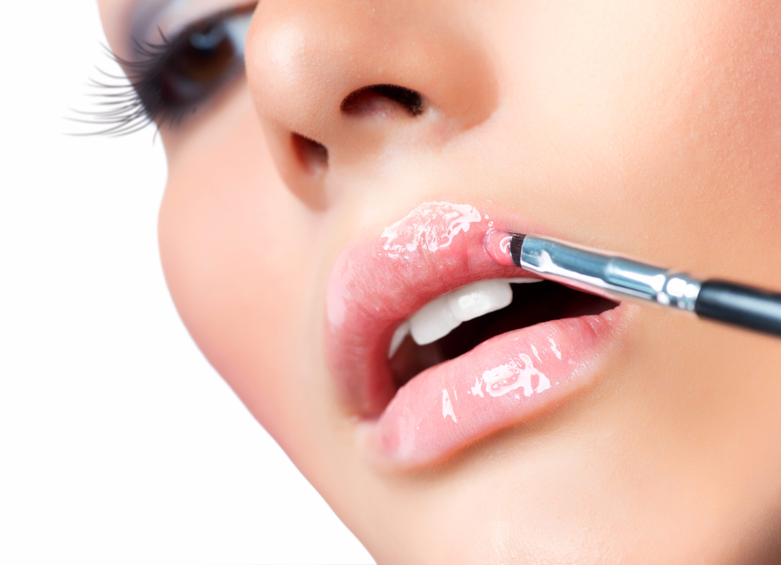 A close-up of a woman applying glossy, vibrant lip gloss formulated with BioconColors high-purity natural colorants, showcasing intense shine and botanical origin.